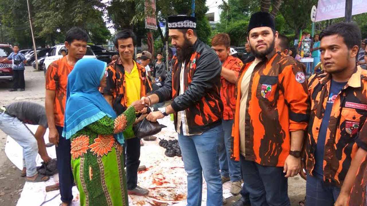 Ketua PAC PP Medan Barat M Rahmaddian Shah SH saat menyerahkan daging qurban kepada seorang ibu. (Foto: ingot simangunsong)